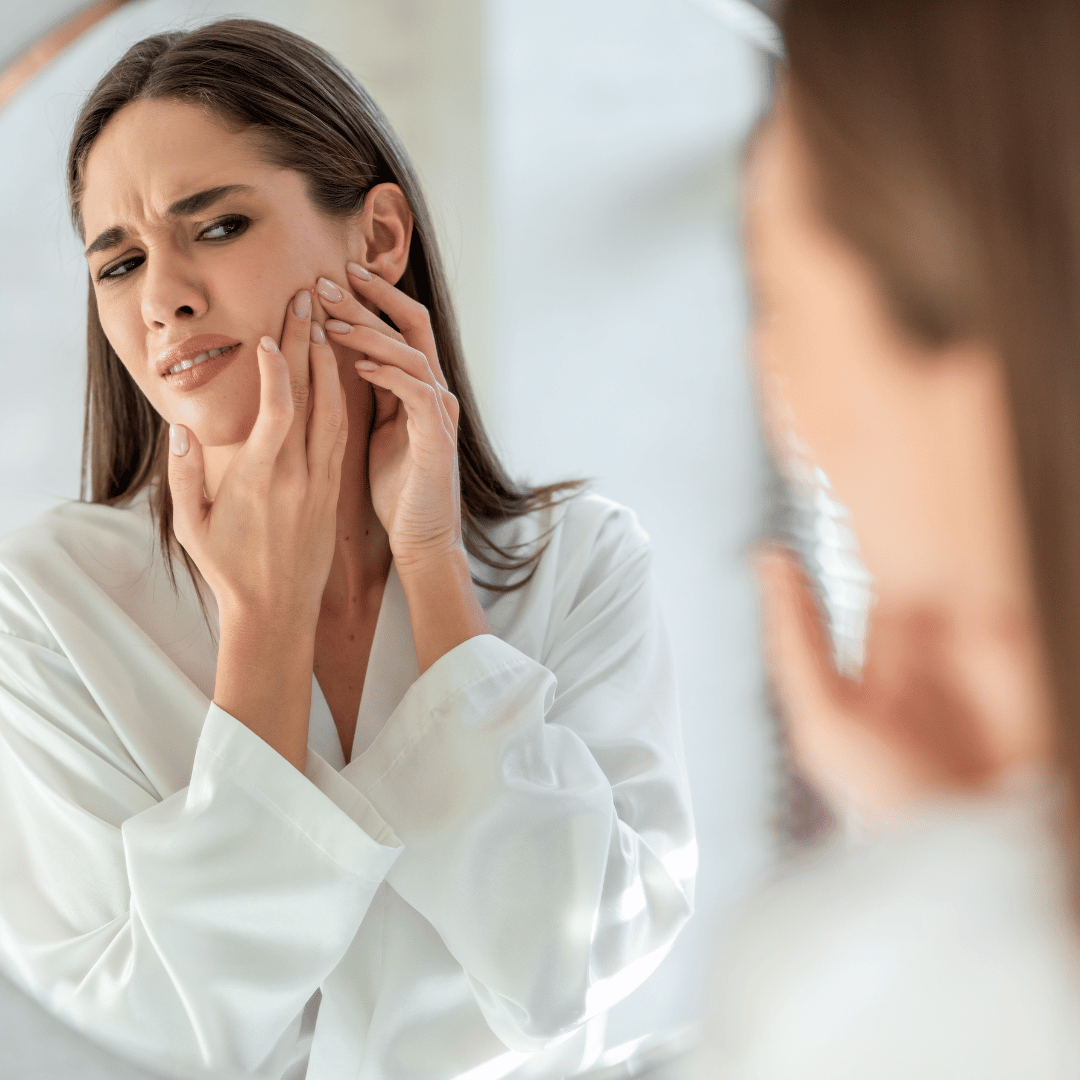 Woman frustrated with skincare routine not working looking in mirror