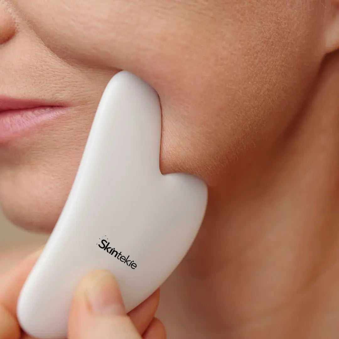 Gua sha gently massaging the face