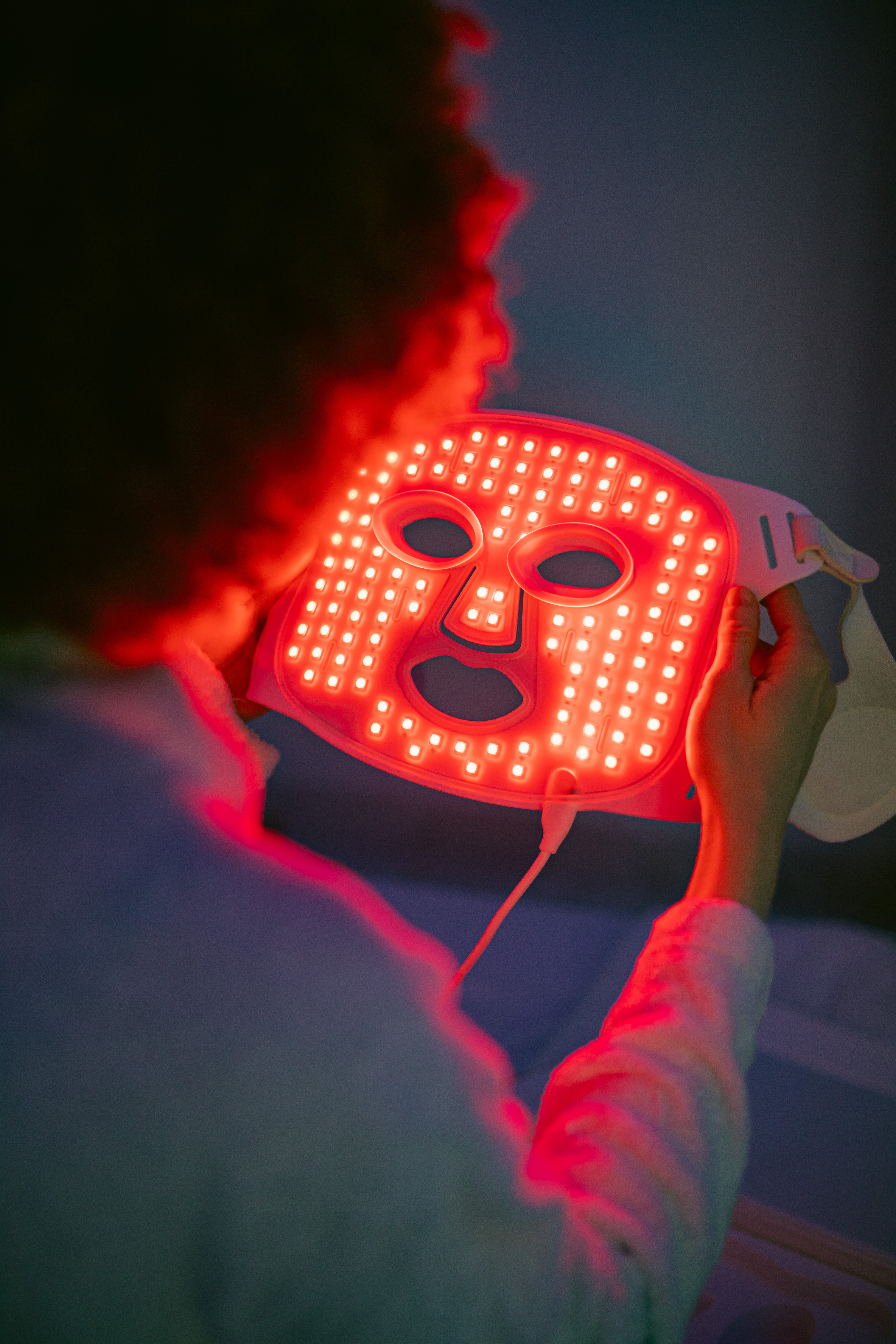 A woman holding the Redlight therapy face mask by Skintekie